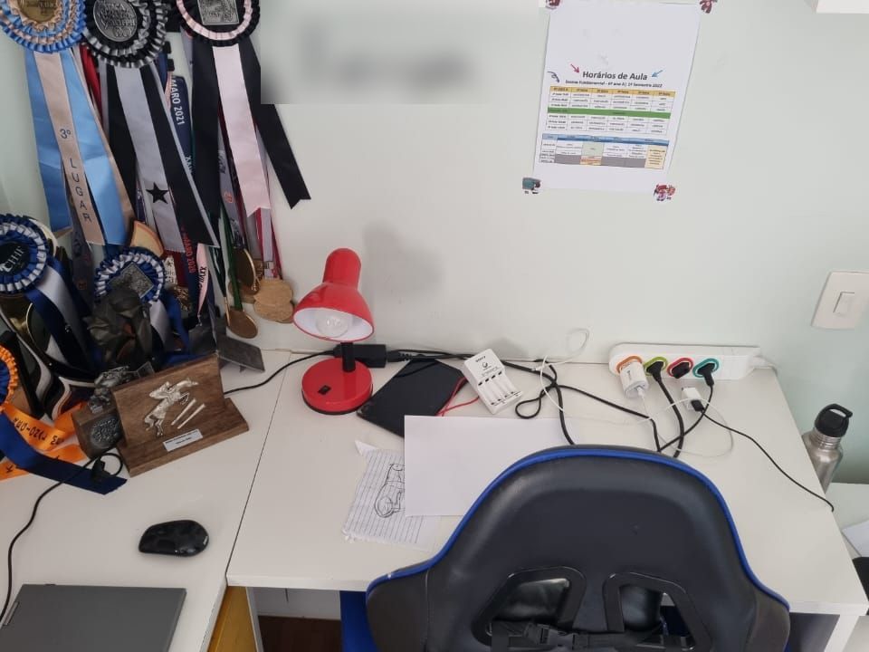 Antes: escrivaninha branca com fios soltos e medalhas penduradas na parede
