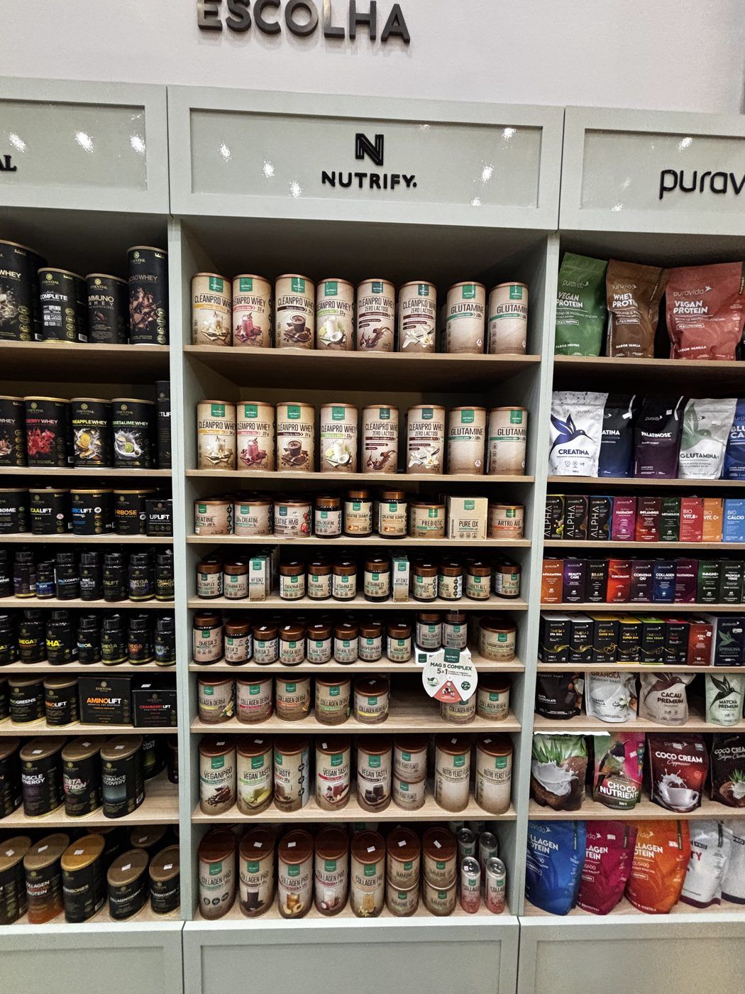 Estante alta e iluminada da loja Vila do Bem, com produtos organizados por categoria