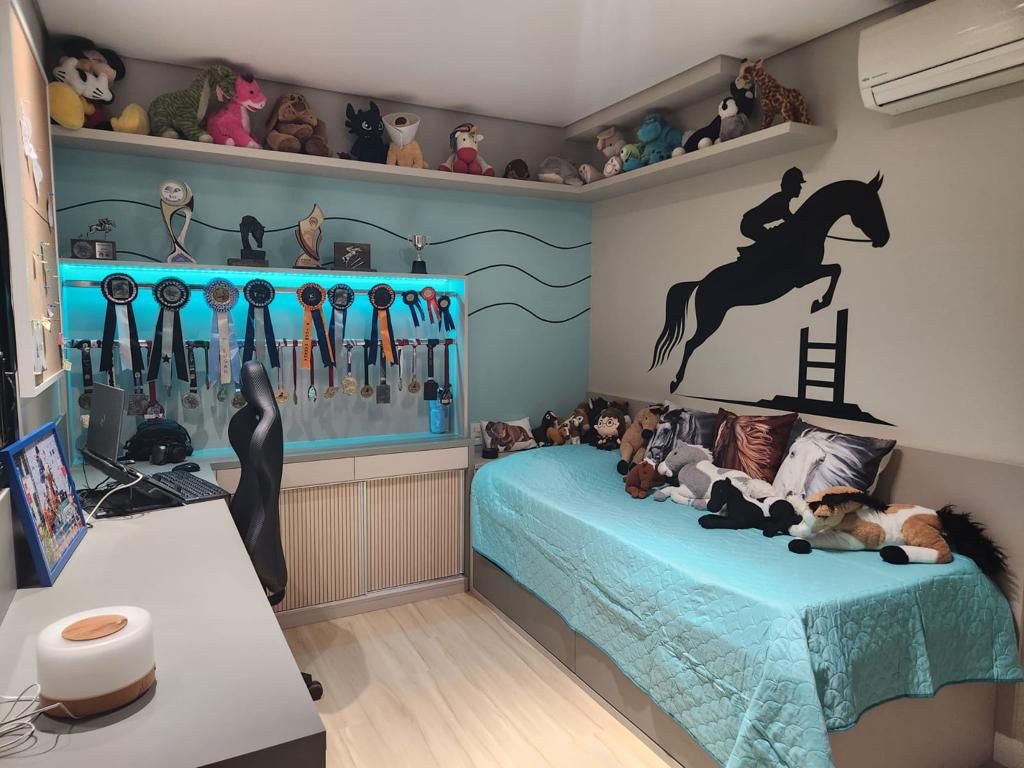 Quarto com cama azul, painel iluminado de medalhas e adesivo de cavalo na parede